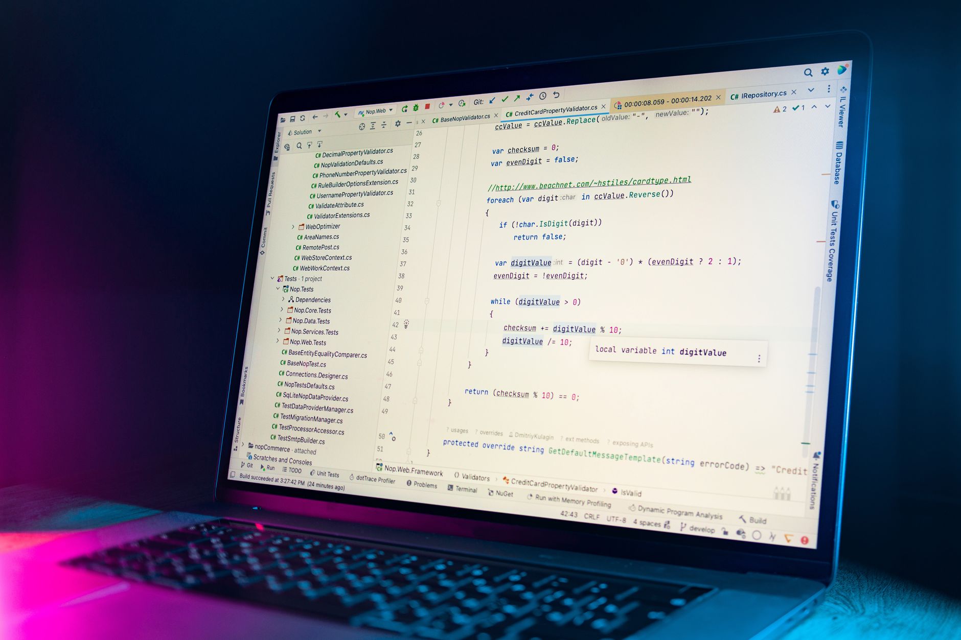 A developer debugging code on a laptop while a phone shows a UI screenshot